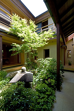 楓燕居・中庭.モミジが植えられた中庭には風の良く通る回廊.そこに蹲つくばいと灯籠とうろう.テーブルと椅子が置かれ朝食やお茶が楽しめる.中庭に面する開口部には風の通りが良い銅網を用いた網戸